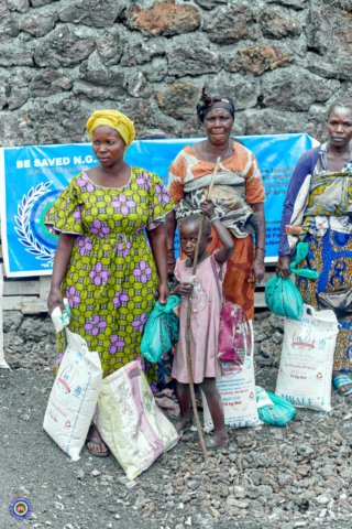 a group of women and a child standing in front of a sign for Bsaved